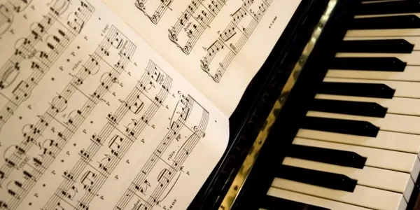 Sheet music resting beside piano keys